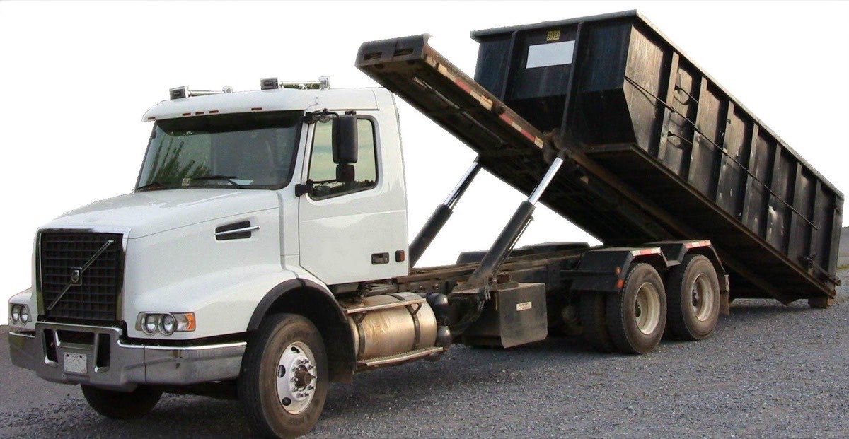 Roll-off truck setting down an open container for a scrap metal job site